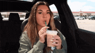 a woman in a car drinking from a plastic cup