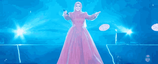a woman in a pink dress singing into a microphone on a stage