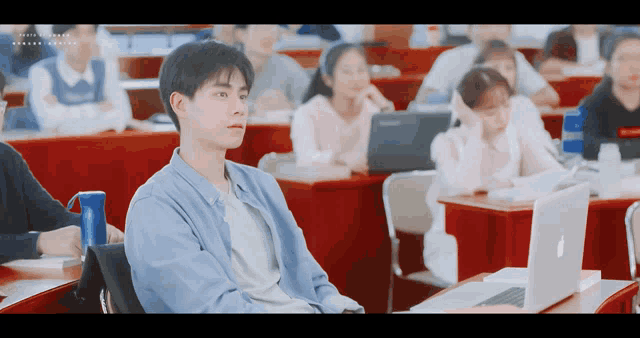 a man sits in a classroom with a laptop
