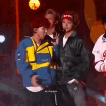 a group of young men are standing next to each other on a stage in front of a microphone .