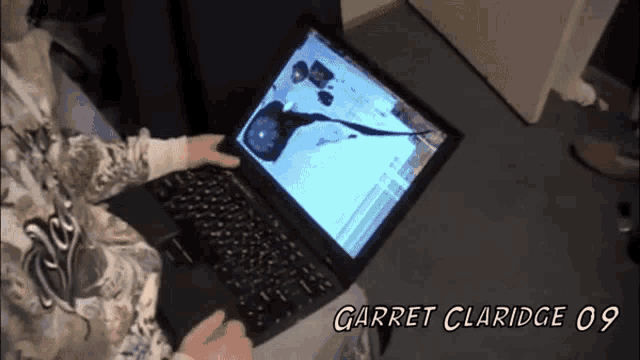 a person is using a laptop that has a broken screen and the name garret claridge 09