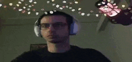 a man wearing headphones is dancing in front of a christmas tree .
