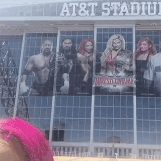 a woman with pink hair is standing in front of an at & t stadium .