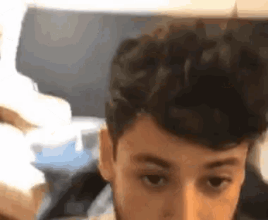 a close up of a young man 's face with his eyes closed and his hair in a bun .