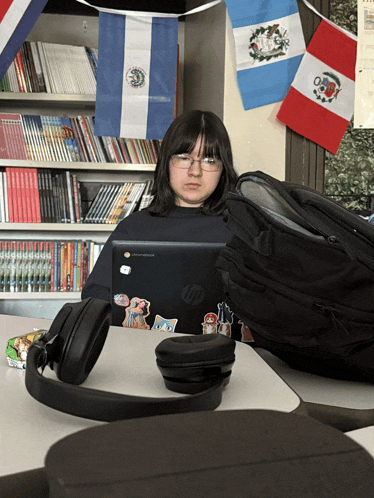 a girl sits at a desk with an hp laptop on her lap