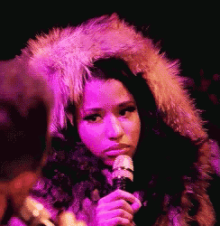 a woman wearing a fur coat is holding a microphone in her hand .