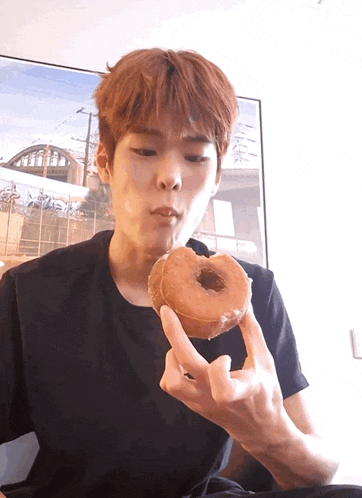 a young man is eating a donut in front of a picture of a bridge
