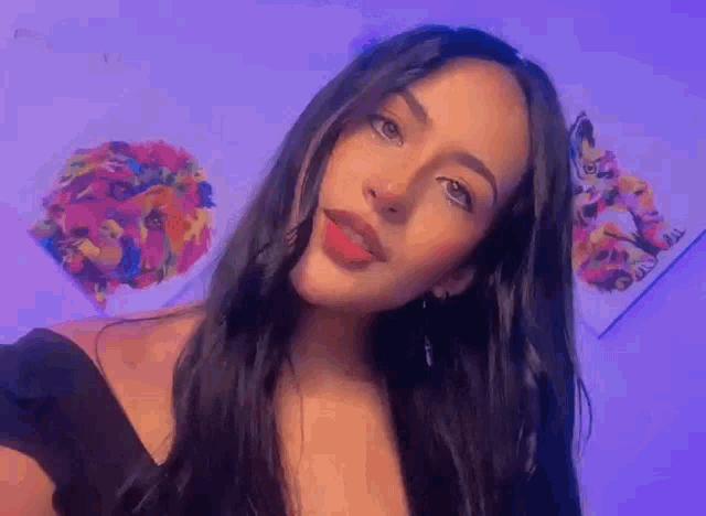 a woman with long black hair is taking a selfie in front of a purple wall .