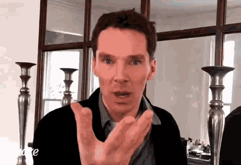 a man is making a funny face while standing in front of a mirror and candlesticks .