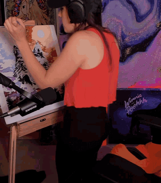a woman wearing headphones is painting on a canvas with a shure microphone