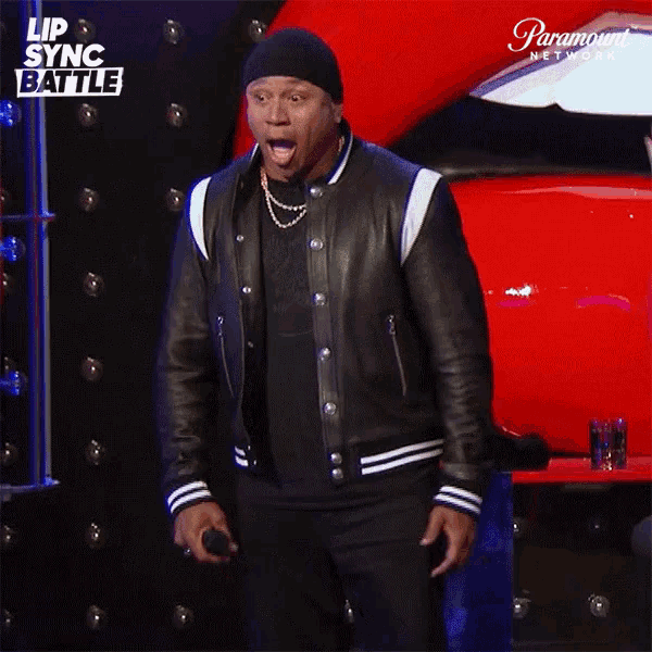 a man stands in front of a red car and a sign that says lip sync battle