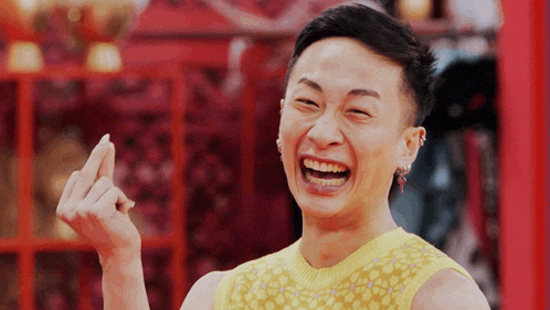 a man wearing a yellow tank top is laughing and making a middle finger gesture