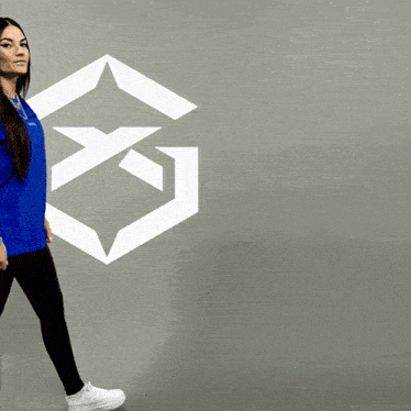a woman in a blue shirt is walking in front of a white g