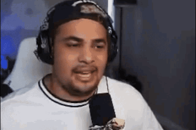 a man wearing headphones and a hat is speaking into a microphone .