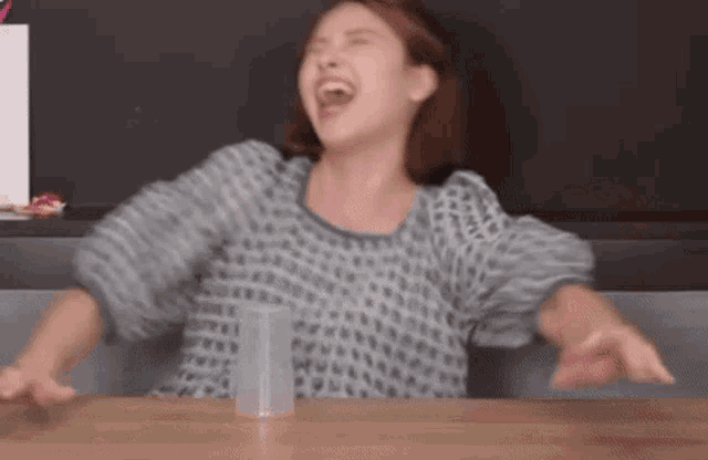 a woman is sitting at a table with her arms outstretched .