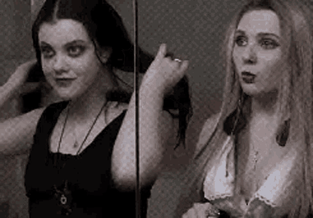 two women are standing next to each other in front of a mirror . one of the women is looking at her hair .