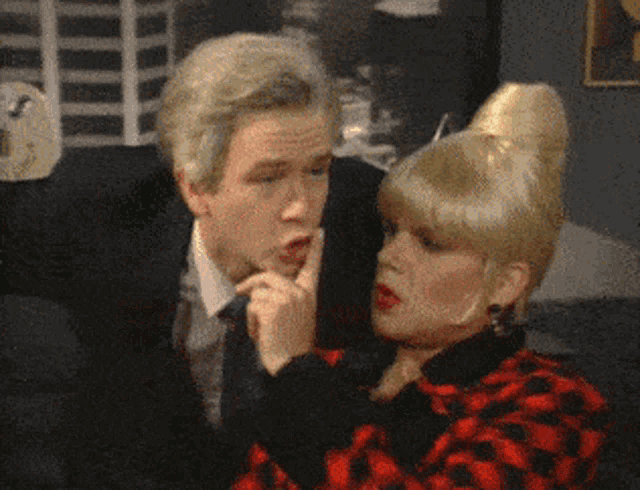 a man in a suit and tie is talking to a woman in a red and black dress