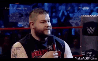 a man is talking into a microphone in a wrestling ring