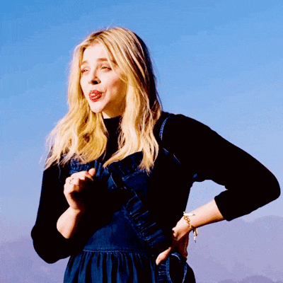 a woman wearing a black turtleneck and a denim dress with her hand on her hip