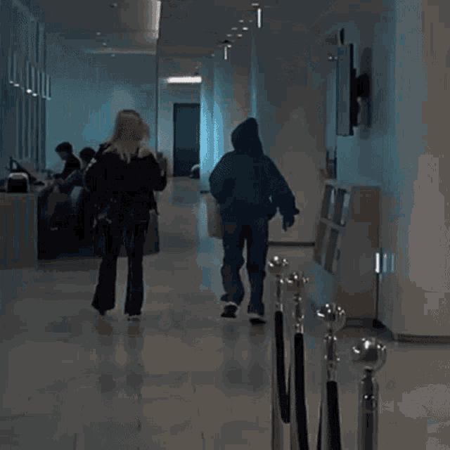 a man and a woman are walking down a hallway in a building