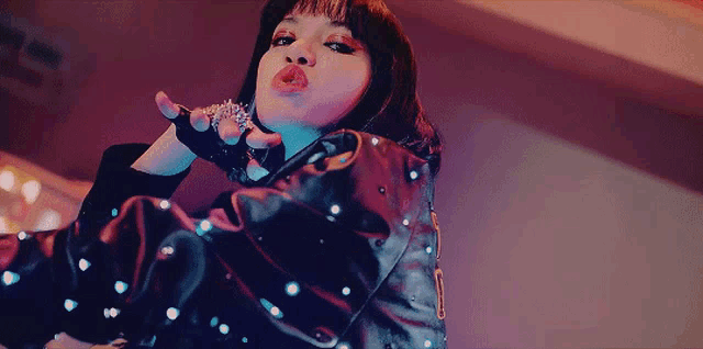 a woman blowing a kiss while wearing a leather jacket and gloves