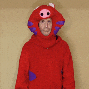 a man is wearing a red costume with a pig hood