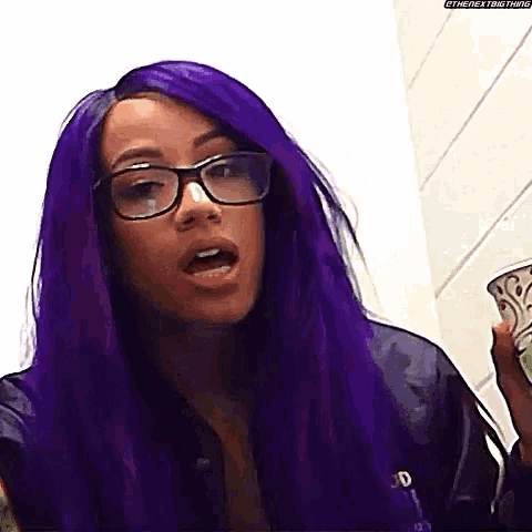 a woman with purple hair and glasses is holding a bowl .