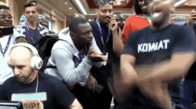 a man wearing a kombat shirt is dancing in a crowd of people .