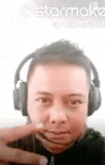 a man wearing headphones and a headset is making a face .