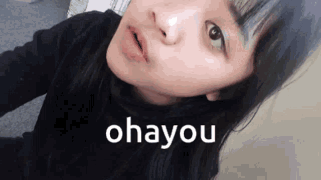a close up of a girl taking a selfie with the words ohayou written on the bottom .