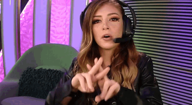 a woman wearing headphones and a leather jacket is making a peace sign with her hands