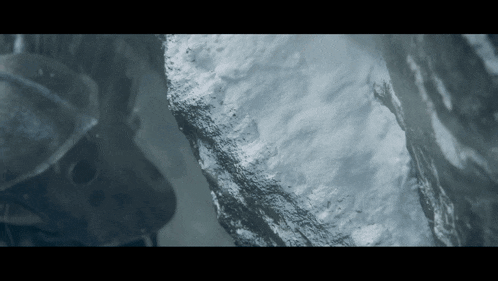 a close up of a rock with snow on it and a person in the background