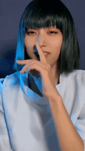 a woman with green hair and bangs is holding her finger to her mouth
