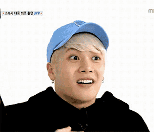 a young man wearing a blue hat and black hoodie