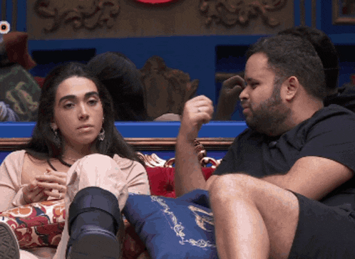 a man and a woman are sitting on a couch and the man is pointing at the woman