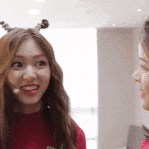 a woman wearing a red sweater and a microphone looks at another woman