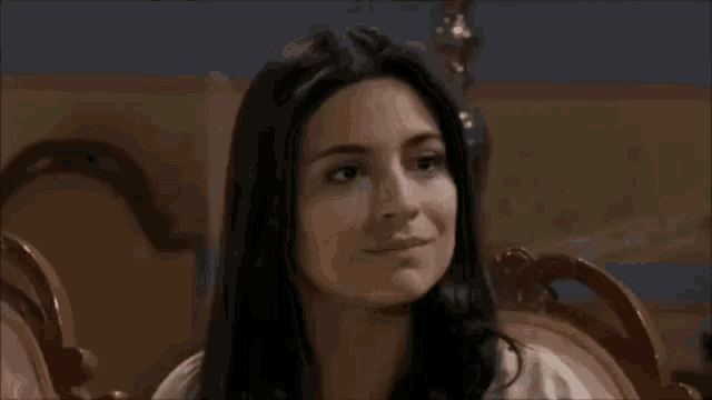 a woman is sitting in a chair smiling and looking at the camera .