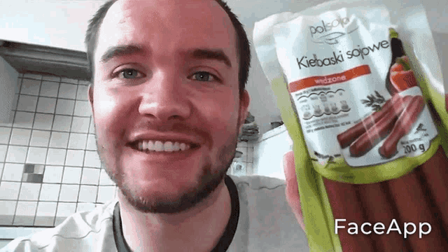 a man holding a bag of kiebaski sojowe sausages