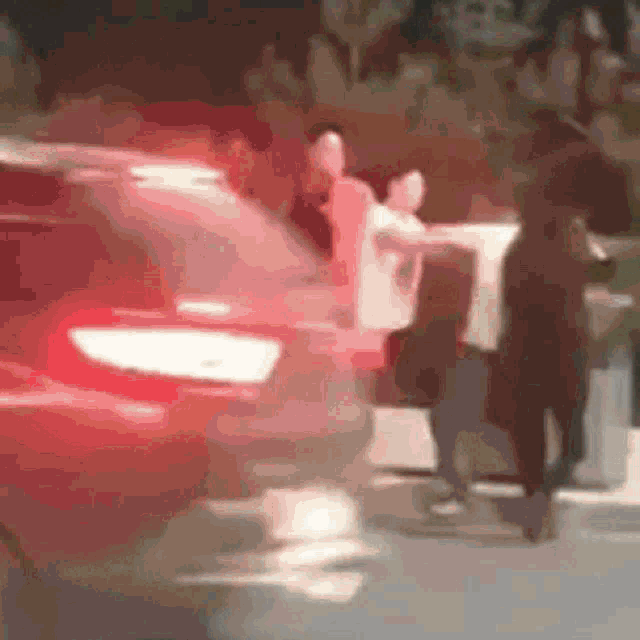 a blurry picture of a red car driving down a street