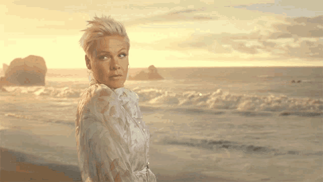 a woman in a white dress is standing on the beach