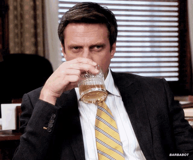 a man in a suit and tie drinking from a glass with barbabot written on the bottom