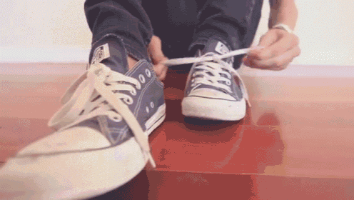 a person is tying a pair of blue converse shoes