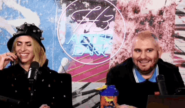 a man and a woman are sitting in front of microphones in front of a neon sign that says h3