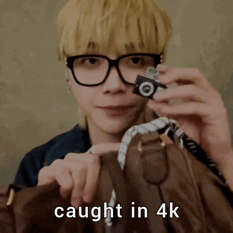 a man wearing glasses is holding a small camera over a brown purse with the words caught in 4k below him