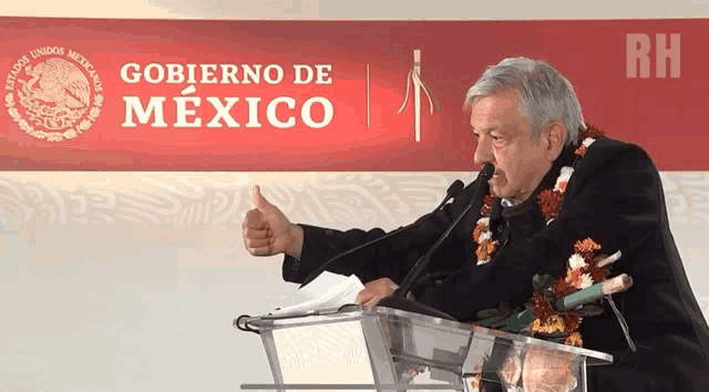 a man giving a thumbs up in front of a sign that says " gobierno de mexico "