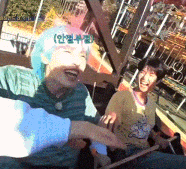 a woman with blue hair is laughing while riding a roller coaster with another person .