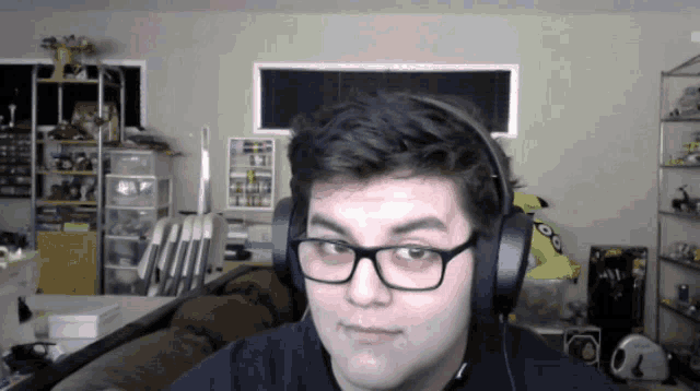 a young man wearing headphones and glasses looks at the camera