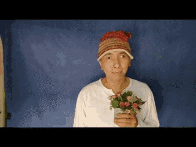 a woman wearing a knitted hat holds a vase of flowers