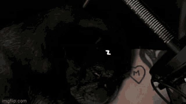 a black dog sleeping next to a person with a tattoo of a heart and the letter m