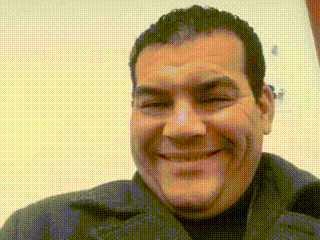 a man in a gray coat is smiling and looking at the camera